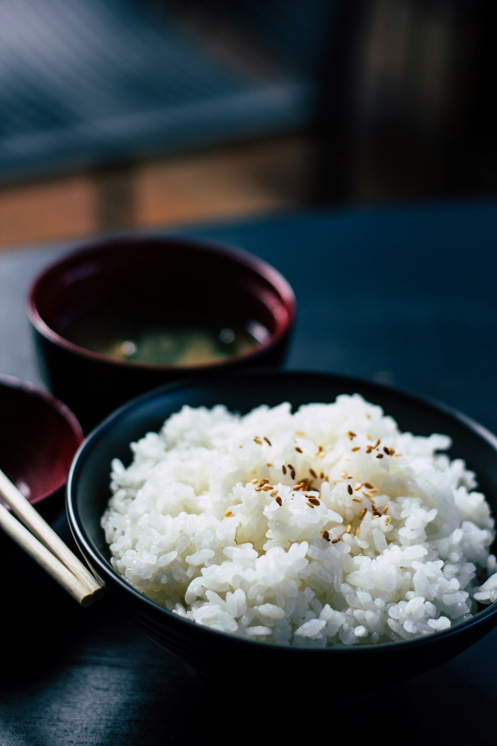 A bowl of steamed rice and fresh rotis on a dark table