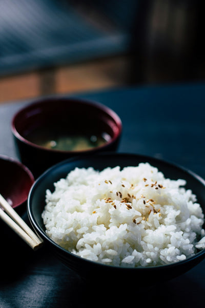 A bowl of steamed rice and fresh rotis on a dark table
