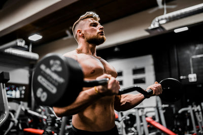 A lifter holding a muscle under controlled tension in a dark, minimal gym
